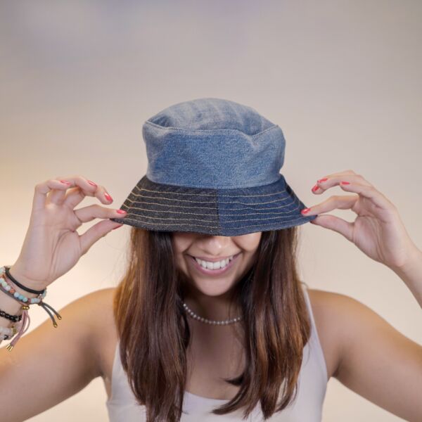 Mujer con bucket hat o gorrito de mezclilla reciclada lista para el verano y disfrutar del sol